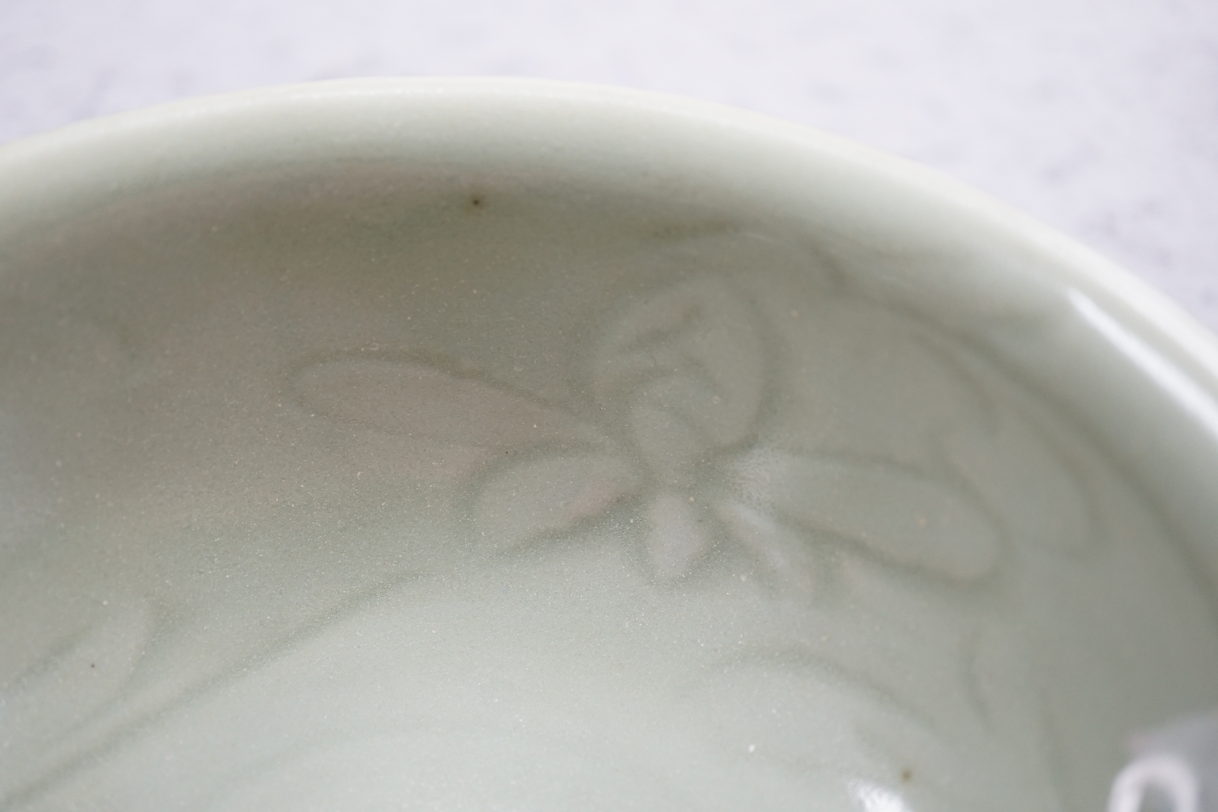 A Chinese Longquan celadon bowl, the interior carved with lotus flowers and the exterior with foliate lappets, 15.2cm diameter., Provenance - Robert Ricketts collection, formerly sold by Robert McPherson, London and S. M